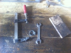 un serre-joint, une clé plate de 14, un collier et une cale de bois